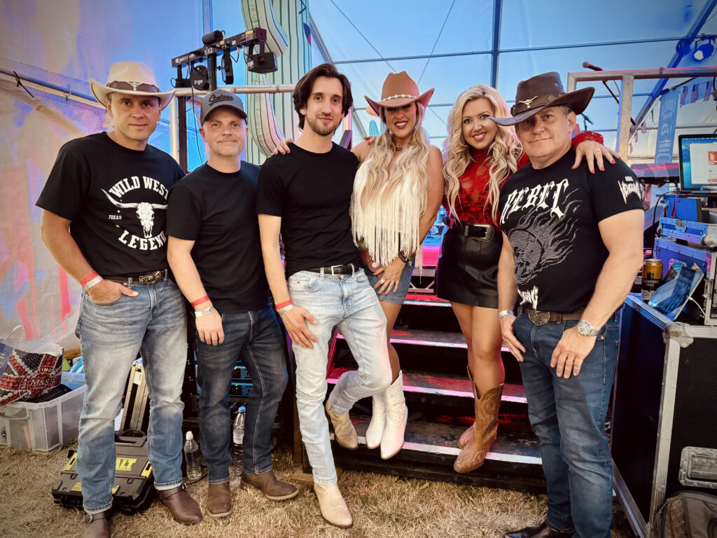 The Wild Ones Country Band standing backstage at a UK festival in western-style outfits