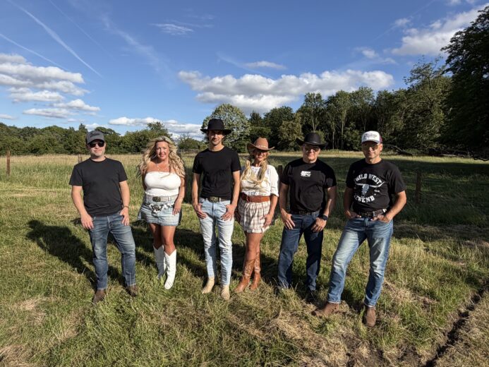 The Wild Ones Country Band standing in a countryside field in western-style outfits
