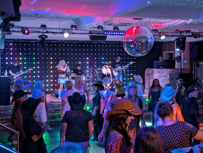 The Wild Ones Country Band performing live to a crowd line dancing at a UK country music event