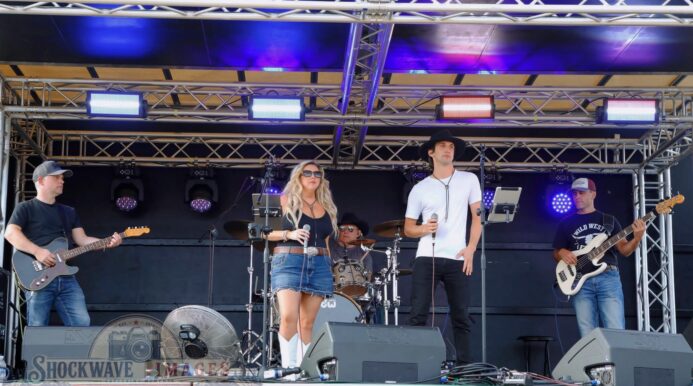 The Wild Ones Country Band performing live on an outdoor stage at a Dorset music event