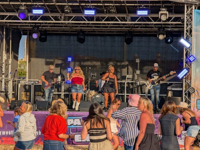 The Wild Ones Country Band performing live on an outdoor stage at a Exeter music event